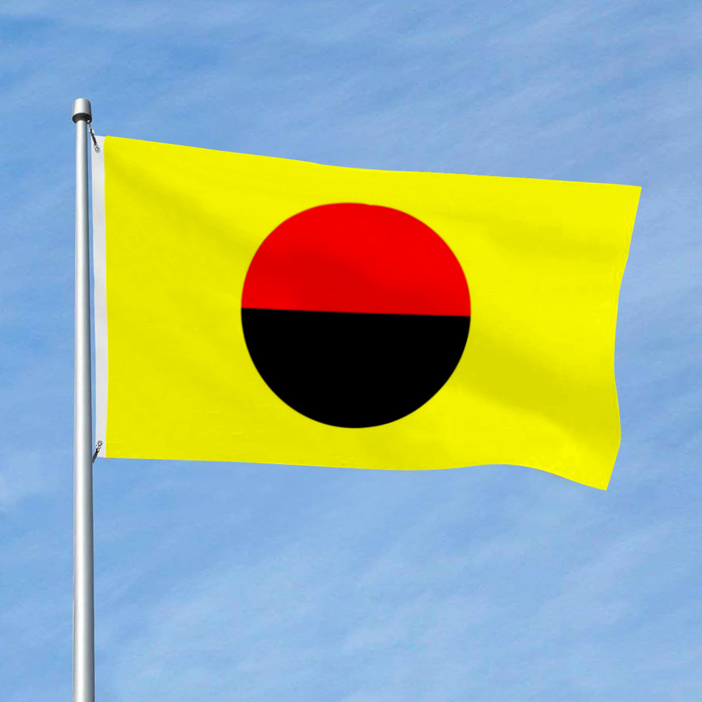 Yellow flag with a large red and black circle centered, flying on a pole against a blue sky.