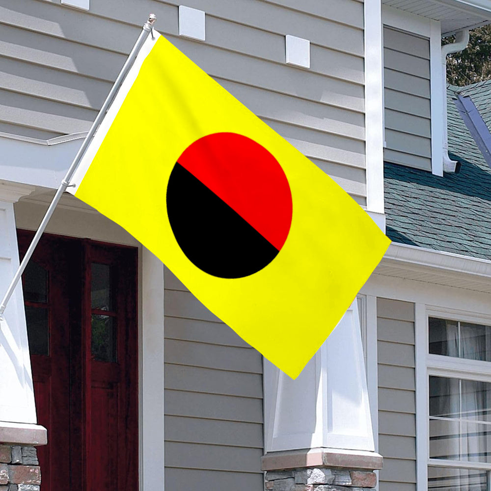 Yellow flag with a red and black circle in the center, mounted on a white house exterior.