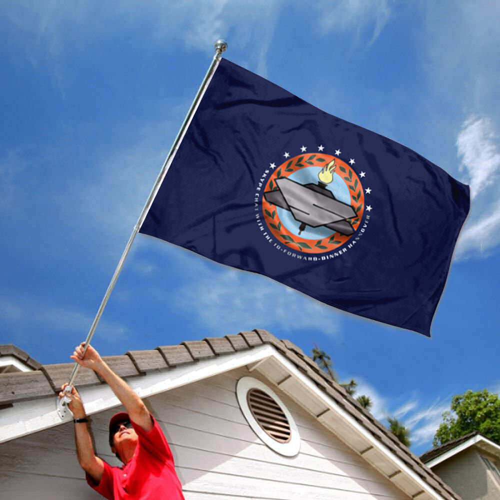 Dark blue flag with circular emblem featuring a futuristic silver spaceship and orange accents, flying against a clear blue.