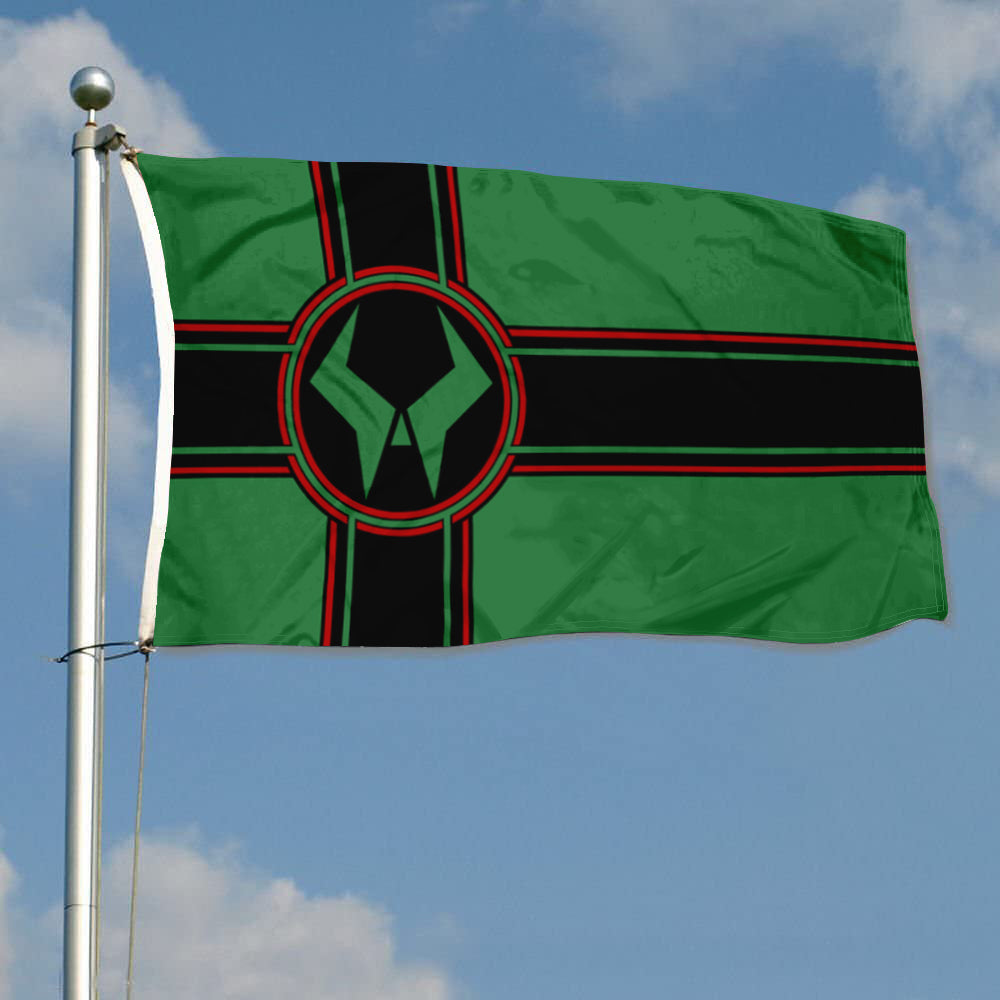 Green Latveria flag with black and red cross and circular emblem on a pole against blue sky.