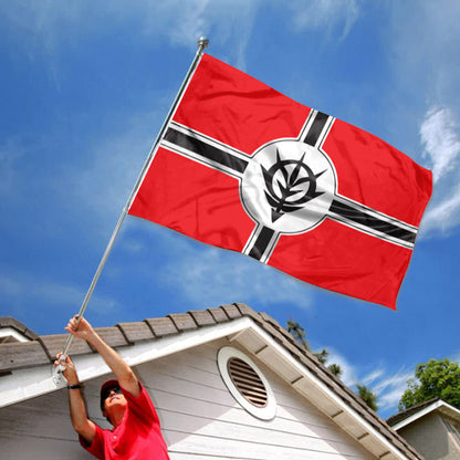 Red Zeon flag with black and white cross and emblem, flying against blue sky above a house roof.